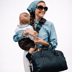 Parent carrying toddler in sling carrier outdoors — NAEVII