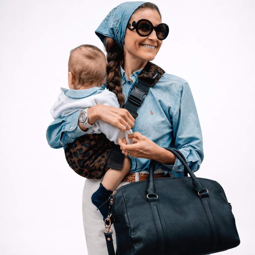 Parent carrying toddler in sling carrier outdoors — NAEVII